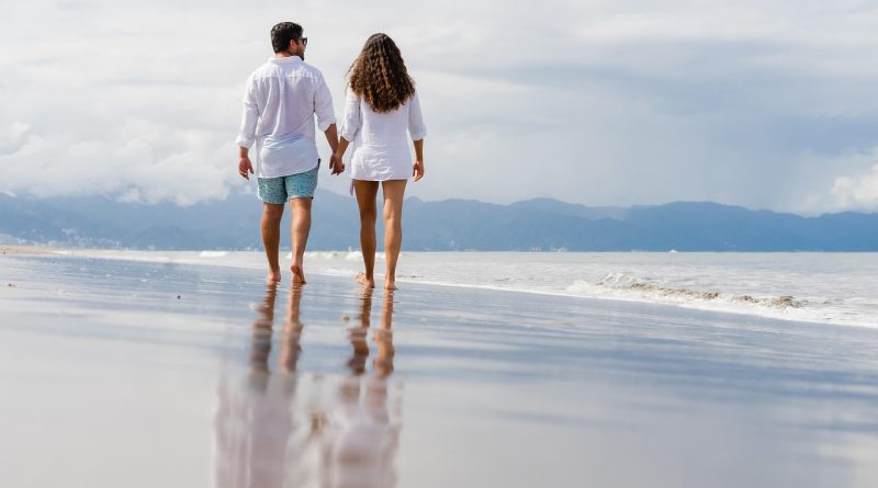 Coppia in spiaggia italiana passeggiano durante vacanza low cost estate 2026