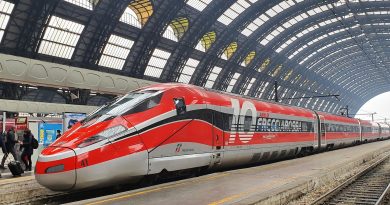 Treno internazionale attraversa un paesaggio alpino durante un viaggio dall'Italia verso l'Europa