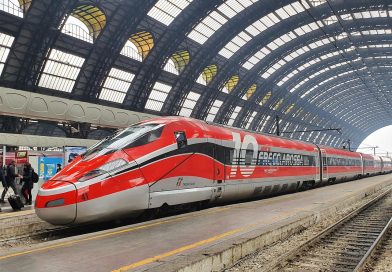 Treno internazionale attraversa un paesaggio alpino durante un viaggio dall'Italia verso l'Europa