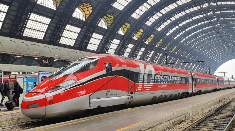 Treno internazionale attraversa un paesaggio alpino durante un viaggio dall'Italia verso l'Europa